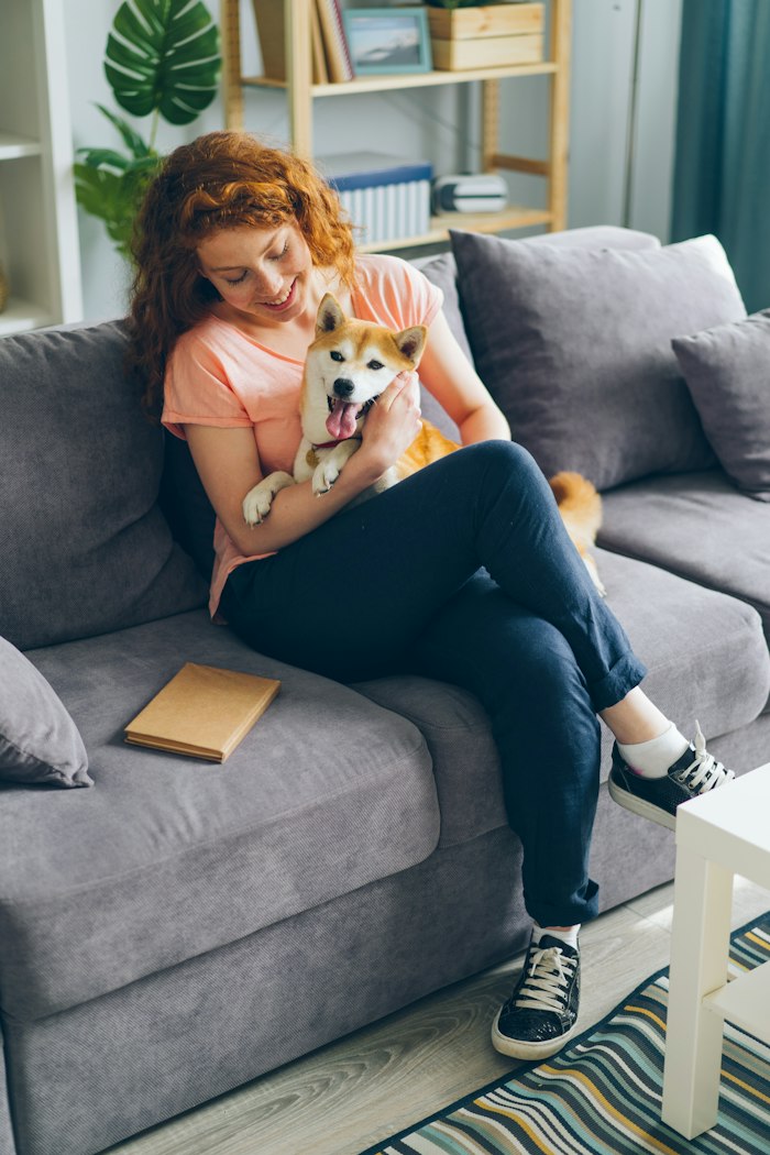 Cliente abrazando a su perro en el sofá