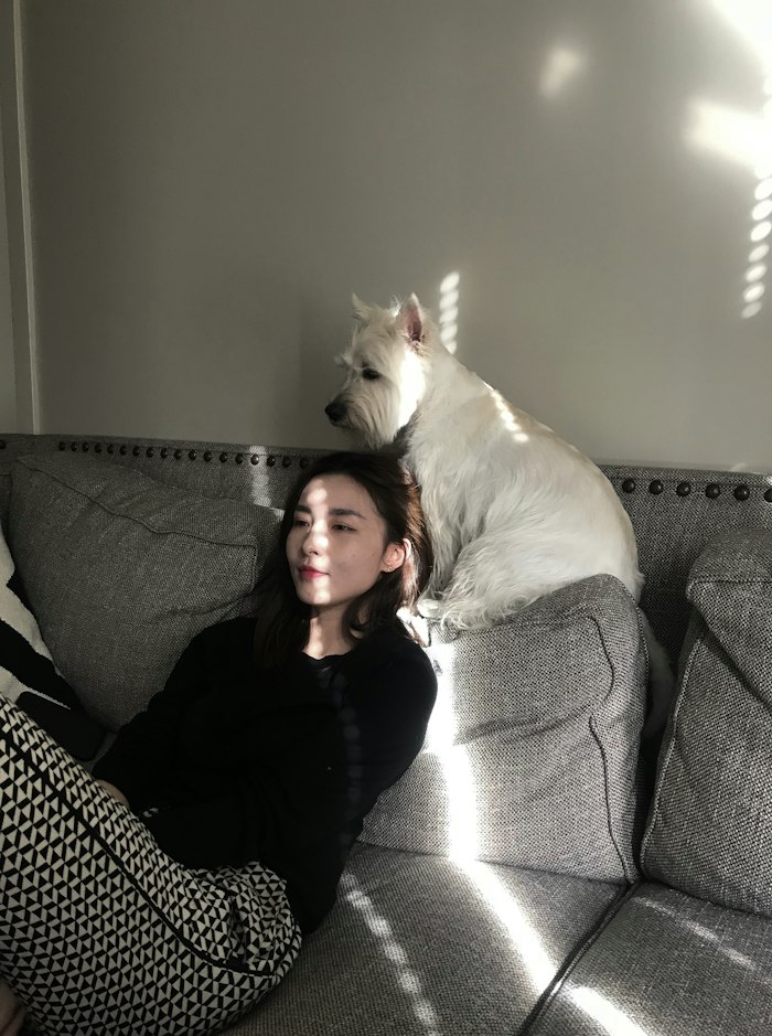Clienta junto a su perro blanco en el sofá